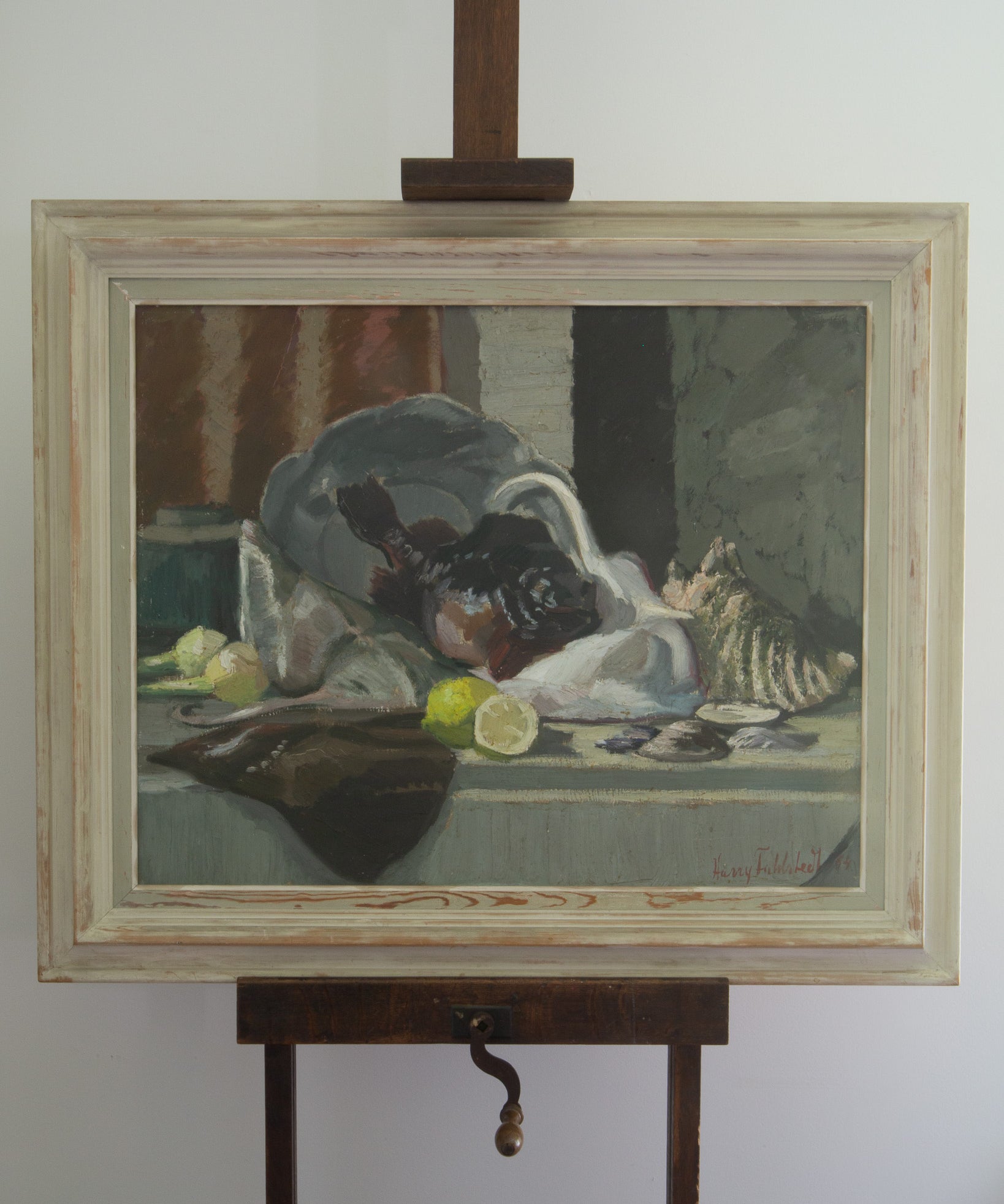 Framed still life painting on an easel against a white wall
