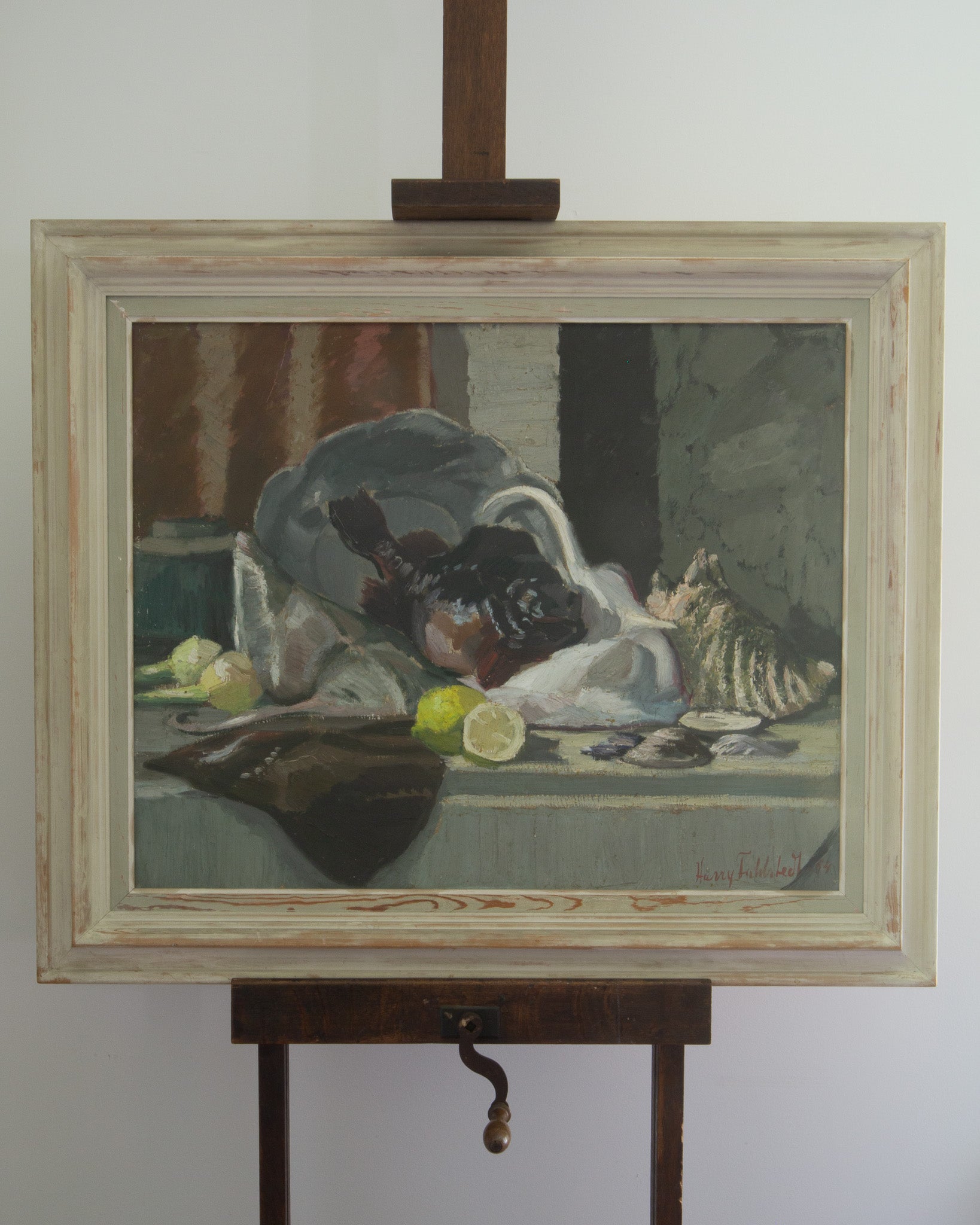 Framed still life painting on an easel against a white wall
